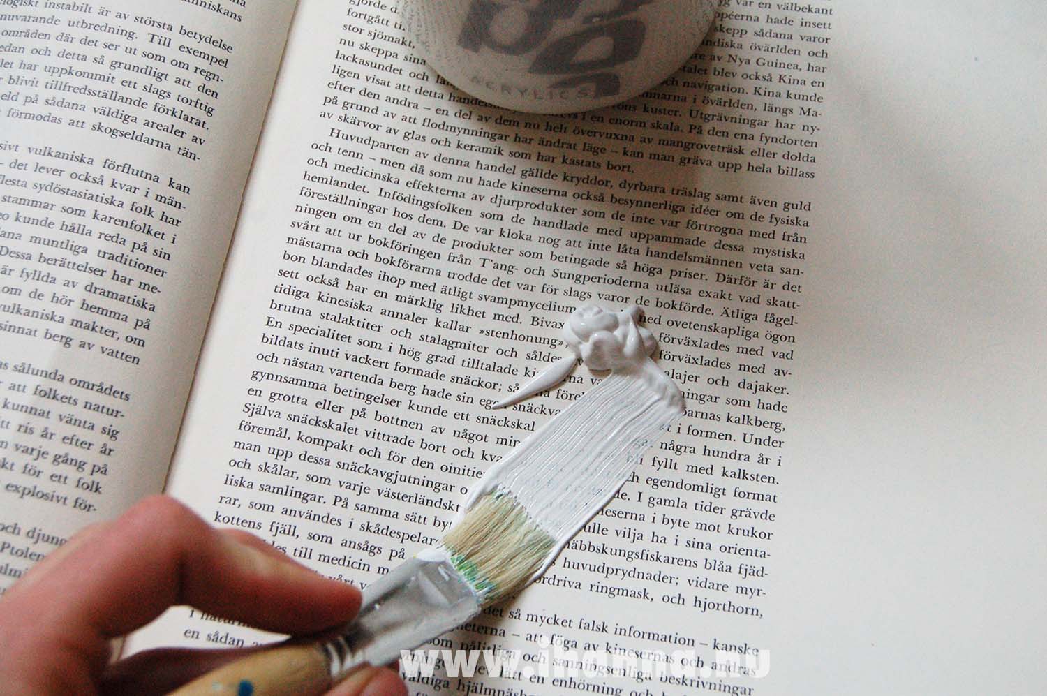 Slapping some white gesso on top of some of the text pages of this altered book (Photo and tutorial copyright Hanna Andersson)